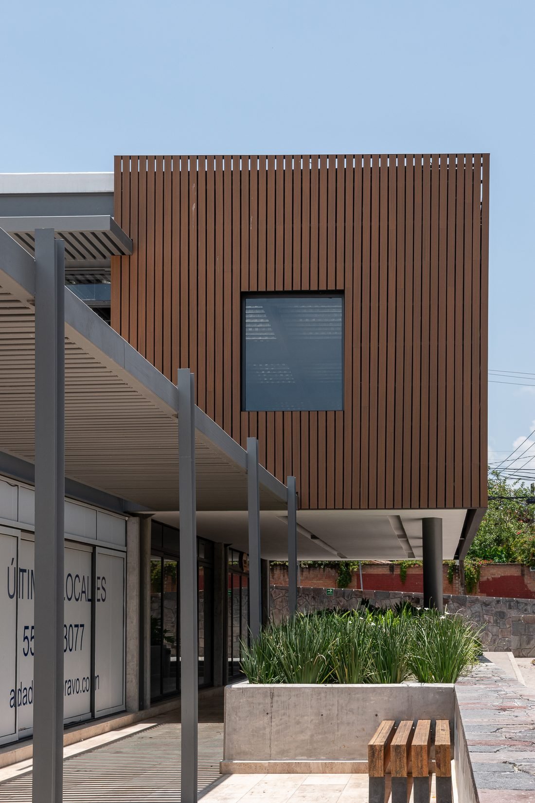Andador y pérgola de la plaza con fachada de madera